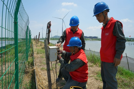2022年7月15日,国网彭泽县供电公司员工在江西彭泽马当镇船形村江水大闸蟹养殖基地,为养殖户检查用电线路,消除用电隐患,保障水产丰收。