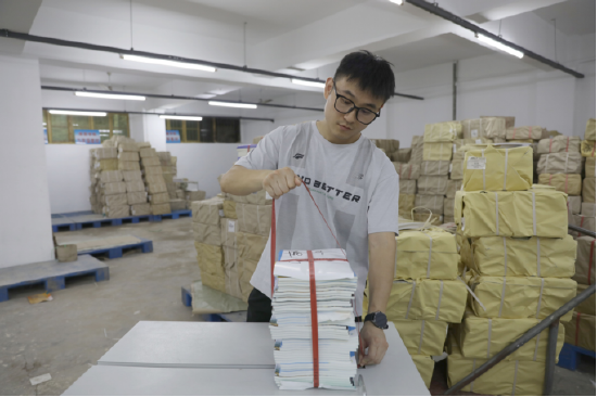 图为:位于江西九江市彭泽县新华书店图书仓库内,正在对需要配送的教材进行打包。(马乐 摄)