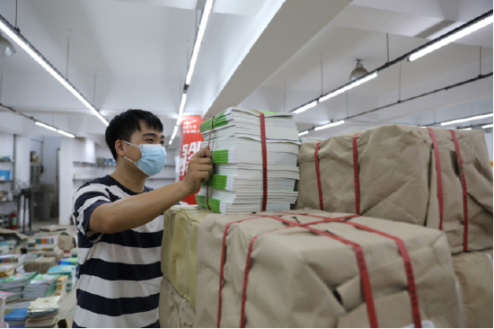 图为:位于江西九江市彭泽县新华书店图书仓库内,正在对刚运送来的教材进行搬运。(彭琴 摄)