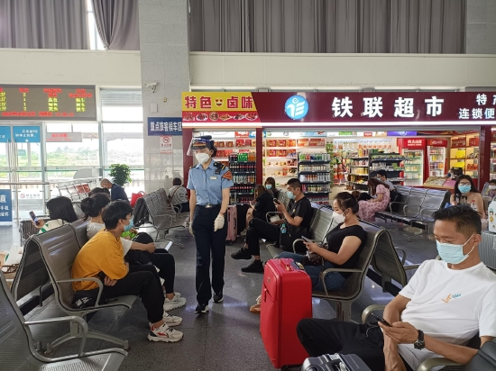 工作人员在候车大厅为旅客宣传防疫政策,做好巡视提醒。王敬忠 摄