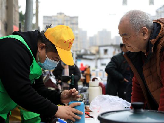 南铁志愿者为居民免费维修豆浆机。摄影:王福斌