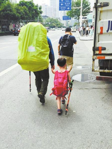 6月14日,来自江西上饶的“中国最小背包客”雯雯随父亲来到成都。图为父女俩行走在蓉城街头。