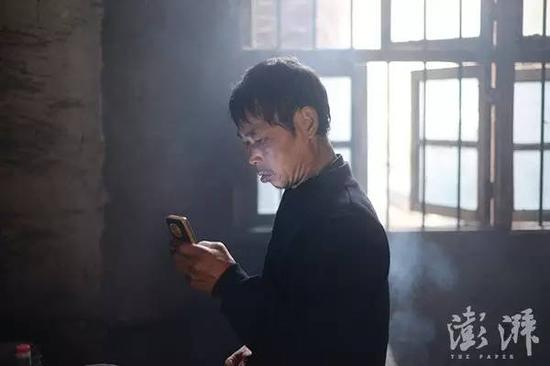 范家发在查看手机信息,在儿子走红网络后,他每天要接听大量的电话和短信。
