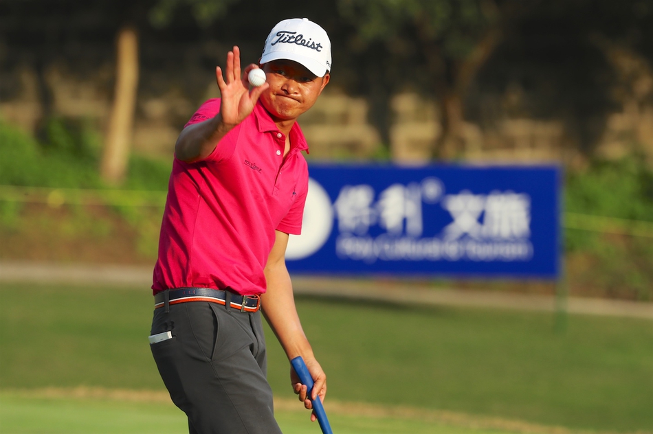 驻场教练陈昌平在果岭边凝神观察推击线路，神情专注，展现出职业球员的严谨态度。