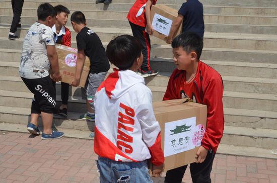 东蛇山子学校同学们将一箱箱爱心图书搬回教室。