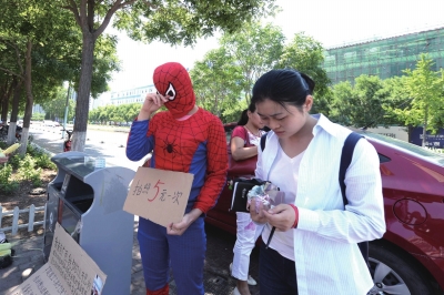 何女士当街扮演“蜘蛛侠”,举牌求路人拍照,为身患噬血细胞综合征的5岁半儿子筹钱治疗。