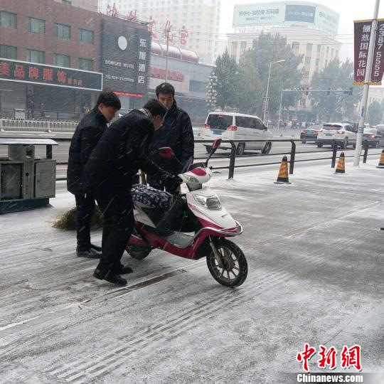 7日，沈阳市和平区，一名电动车驾驶者在路上滑倒后站起。　张颖 摄