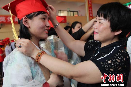 家长为孩子戴上成人帽。 曾蓓 摄
