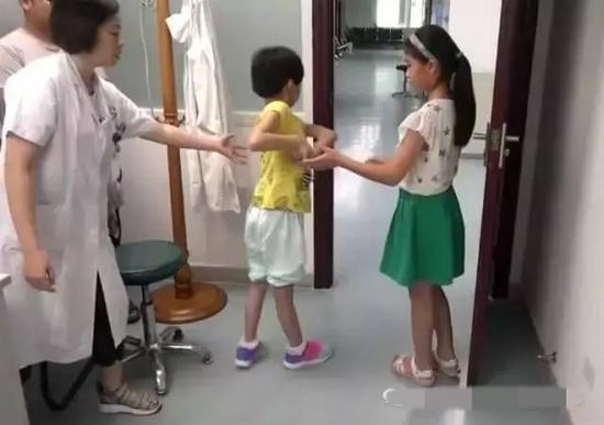 小慧(中)全身扭曲,走路困难,而双胞胎妹妹(右)则完全正常。