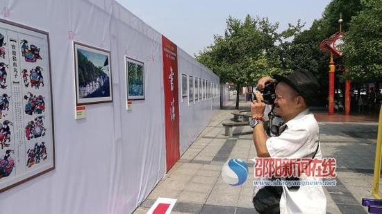 王雄杰老人正在书法美术摄影展上拍摄自己心仪的作品。 贺旭艳 摄
