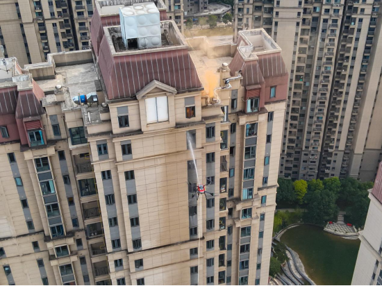 宜昌市消防救援人员在高层住宅建筑灭火演练中，使用无人机从建筑外部协同开展百米高空灭火 杨凌骁/摄
