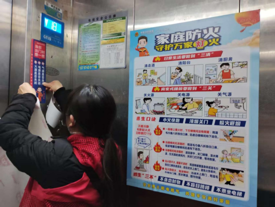 咸宁市消防救援局联合社区志愿者对辖区高层建筑电梯内张贴提示标语。 艾琳/摄