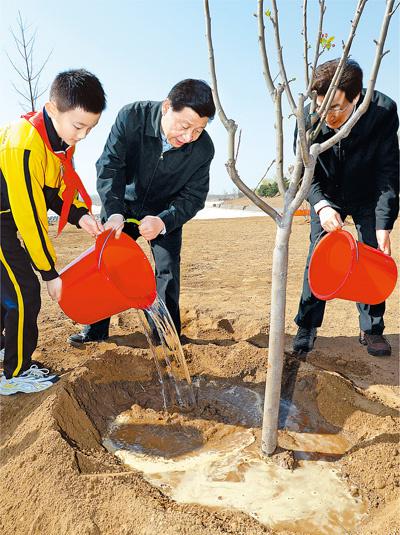 2014年4月4日,习近平同大?#20057;?#36215;给?#36213;?#19979;的树苗浇水。新华社记者 李涛摄