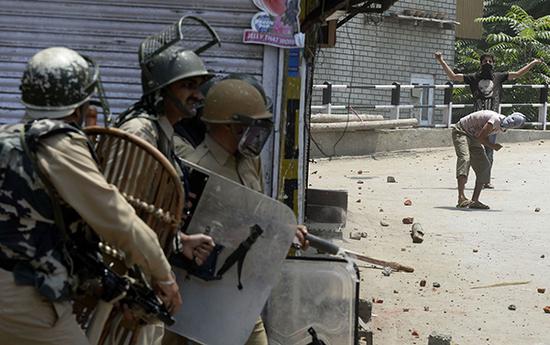 印控克什米尔地区，戴着面具的抗议者朝当地的警察抛掷石块。 视觉中国图