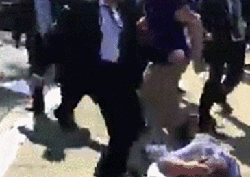 
	冲突现场一名穿西装男子正在猛踢一名抗议者头部 
