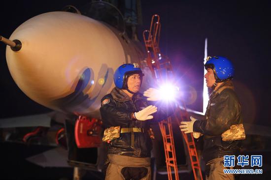 2015年3月4日,“海空雄鹰团”团长陈刚(左)在起飞前向飞行员讲解技战术动作要领。