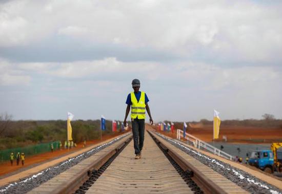 在肯尼亚蒙巴萨─内罗毕铁路铺轨试验段项目现场,一名肯尼亚工人从铁轨上走过/资料图