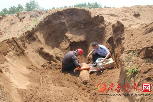 图为排爆专家和民警在沙塘内小心翼翼地安置航弹。