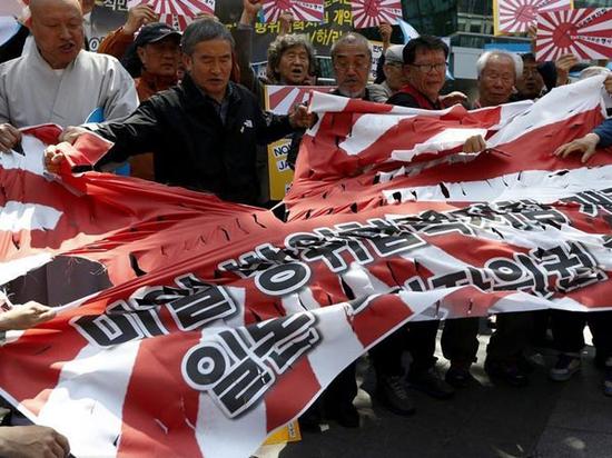 资料图：2015年4月，韩国民间团体聚集在日本驻韩使馆前示威，撕毁旭日旗