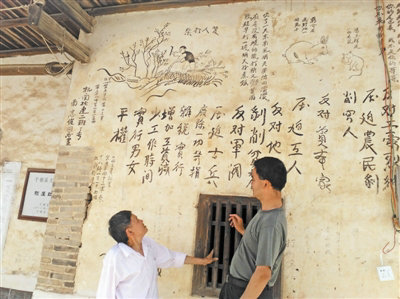 原文配图:赖如亮向笔者介绍他家墙上的红军标语和漫画