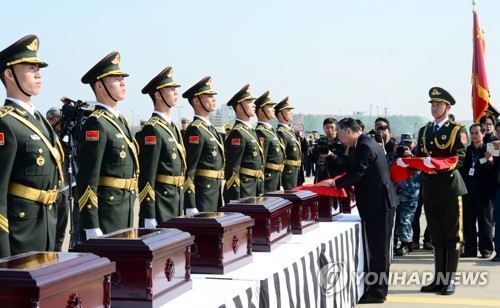 3月22日，在仁川国际机场，韩中举行在韩中国志愿军遗骸交接仪式，中国驻韩大使邱国洪为骨灰盒披上五星红旗。（韩联社）