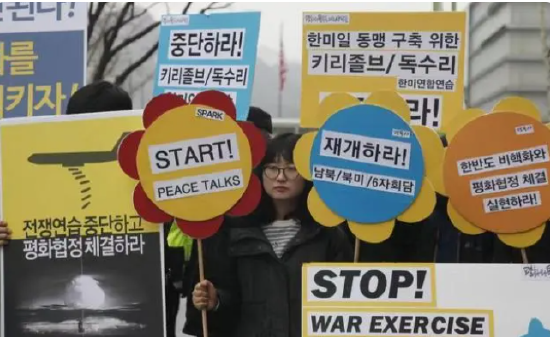 ▲2016年3月7日，在位于韩国首尔的美国驻韩国大使馆附近，韩国民众高举反战标语牌抗议韩美军演。图/新华社