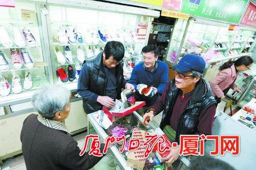 庄老板给顾客拿合适的鞋，两旁的老主顾也留下来帮忙。