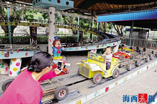 虽然游乐设施已经不运转了,但市民仍带着孩子在中山公园游乐场合影留念。