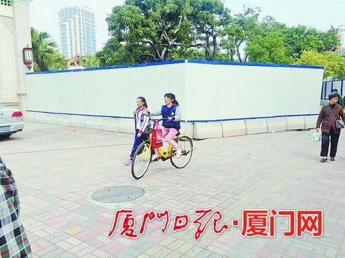一名小学生正在中山公园东门外骑共享单车。