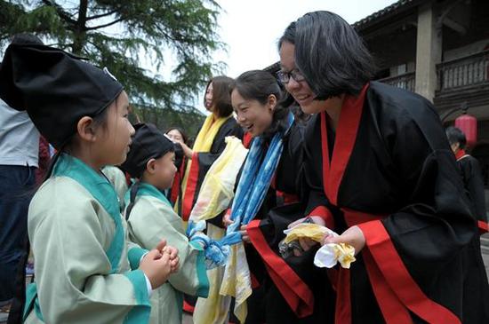 图为身着汉服的小朋友、子女向母亲们行揖礼,并帮母亲戴上亲手制作的围巾