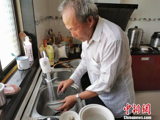 图为裘然安做家务。 陈琼 摄