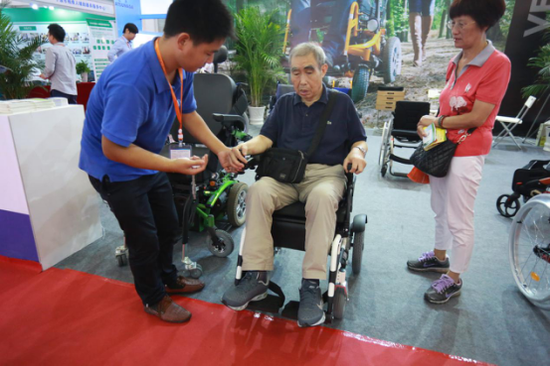 老年人在现场体验可自动升降调节的智能电动轮椅。黄瑞鹏 摄