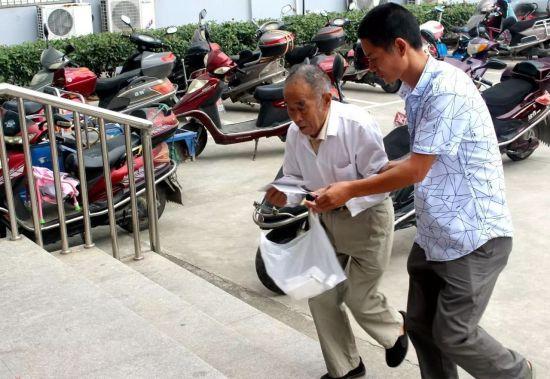 图为娄逢理帮助老人看病就医