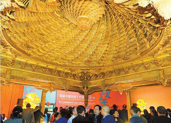 11月10日,人们在首届中国民间工艺精品双年展上展出的千龙万工藻井木雕前驻足。(周建平 摄)