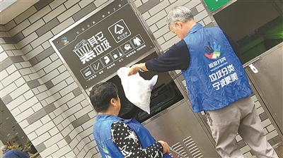前天上午,柴国权、毛亚萍在垃圾房前忙着分类垃圾。(王博摄)