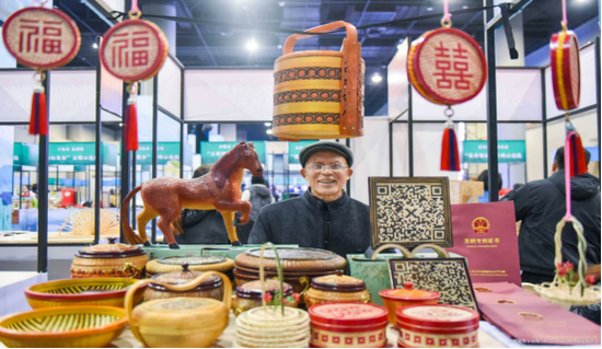 图为现场的游客流连竹编艺术品展区。