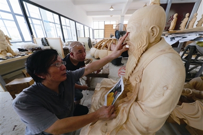黄才良(左一)对徒弟的作品提出意见