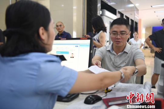 图为周代祥正在办理居住证。 俞靖 摄