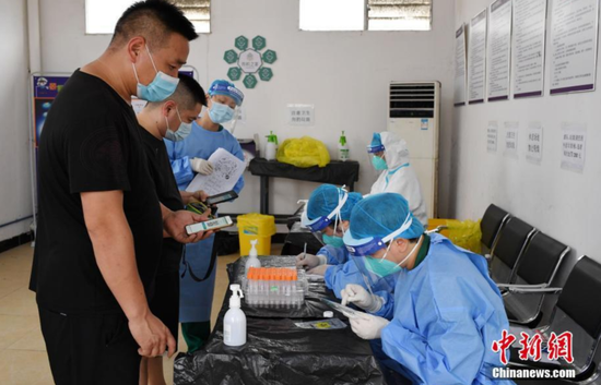 6月2日,广州市花都区工作人员在临时核酸检测点为货车司机登记、确认信息。图/中新网