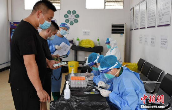 6月2日，广州市花都区工作人员在临时核酸检测点为货车司机登记、确认信息。图/中新网