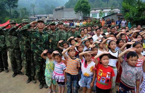 2008年5月24日，解放军战士和四川青川县“猛虎”爱心帐篷小学的师生们一起参加升国旗仪式。图源：刘海峰|新华社