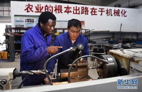 喀麦隆小伙楚柯（左）在湖南农业大学农业机械化工程实训中心向技术员陈昌广学习机床操作（3月14日摄）。新华社记者 李尕 摄