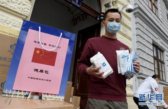4月17日,在奥地利都城维也纳的中国驻奥地利大使馆前,中国留门生吕荟展示使馆发放的“康健包”内的防疫物品。 记华社新者。 郭晨 摄