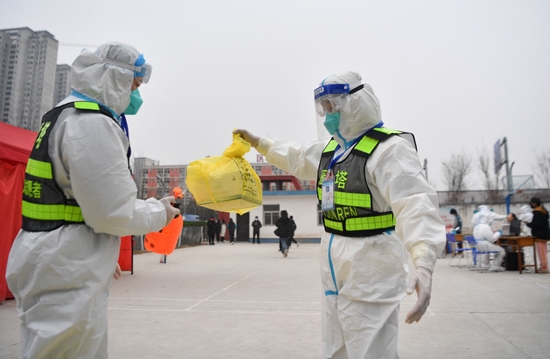 ↑1月7日，西安市雁塔区退役军人志愿突击队队员李龙（左）协助队员邹浩东为核酸检测样本外包装消毒。