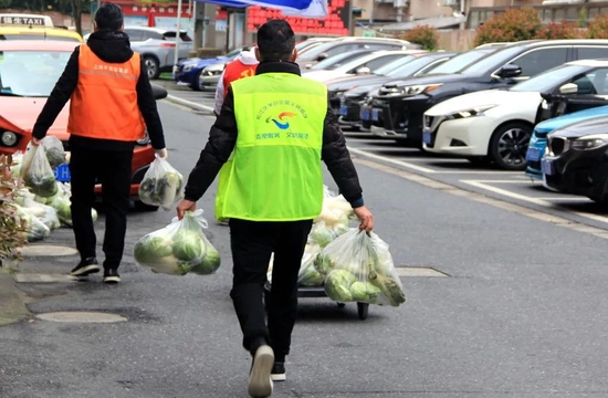  4月15日，上海松江区洞泾镇一小区门口，志愿者和工作人员正在搬运防疫生活物资。