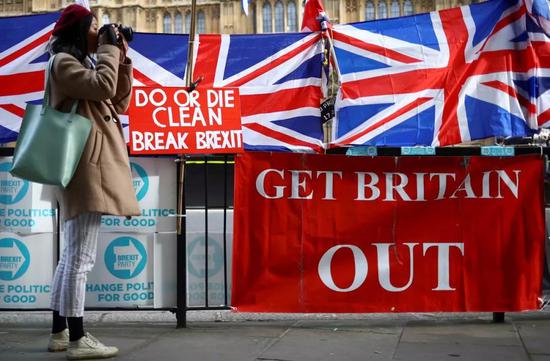 10月28日，在英国伦敦议会大厦外，一名女子站在英国国旗和支持英国“脱欧”的标语旁拍照。新华社/路透