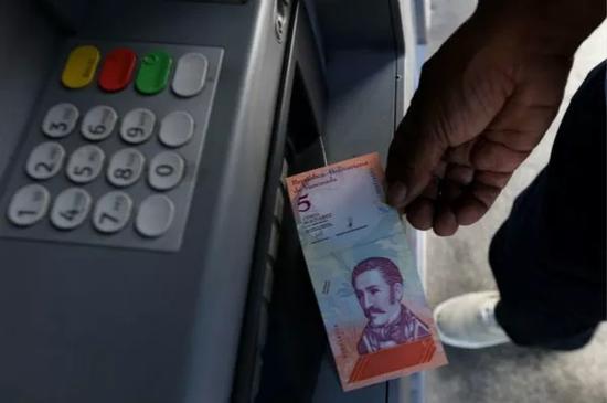 8月20日，在委内瑞拉首都加拉加斯，一名男子从ATM机中取出一张新货币“主权玻利瓦尔”。新华社发（格雷戈里奥·特兰摄）