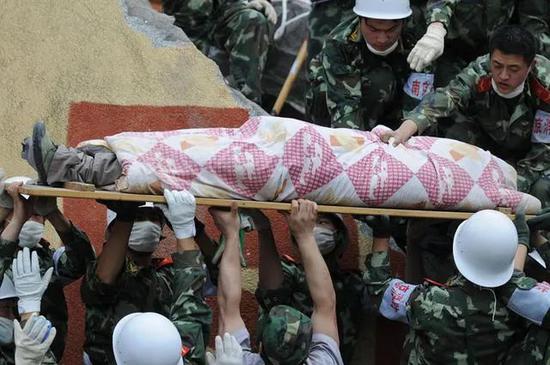 2008年5月15日，消防战士在四川省什邡市蓥华镇云峰化工厂倒塌的宿舍楼废墟中营救出一名生还者。图源：姜帆|新华社