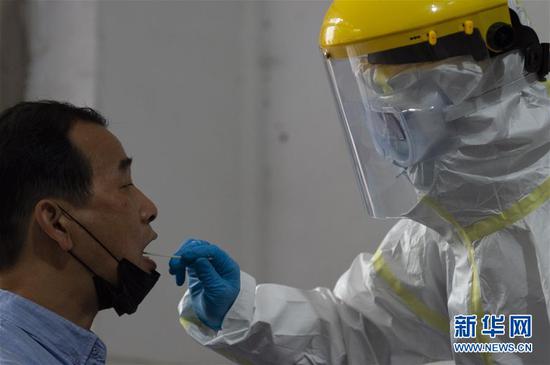 在湖北省襄阳市樊城区检测点,事情职员给一位西席收罗咽拭子(4月18日摄)。新华社发(谢剑飞 摄)
