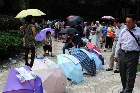 2014年9月27日,上海人民公园相亲角内人头攒动,父母将子女的征婚信息贴在雨伞上。